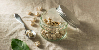 Flat lay of a beef liver gummy jar and spoon on light linen with bright natural light
