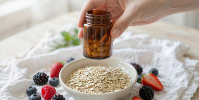 Fair-skinned hand holding a plain supplement jar above gluten-free oats and berries on white linen