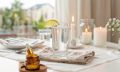 Restaurant table corner with sparkling water and lime, an amber tin and a folded napkin in light