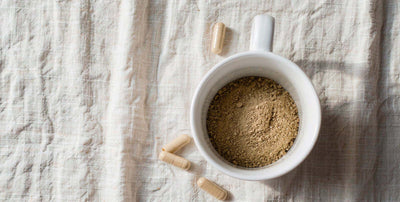 Overhead flat-lay of a dandelion root tea cup and capsules on bright linen, everyday liver botanical