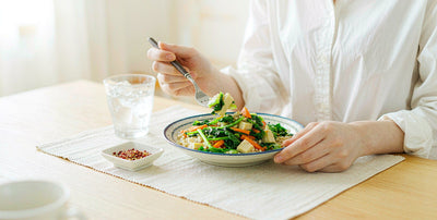 Fair-skinned hands eating a balanced vegetable meal at a bright table, no face visible