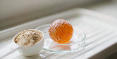 Macro of a plain unlabeled supplement gummy and a scoop of fine powder on a bright white surface
