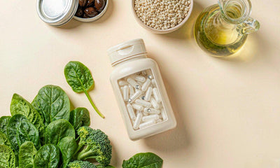 Flat lay of plain capsules with spinach, broccoli, sardines and olive oil on a cream surface