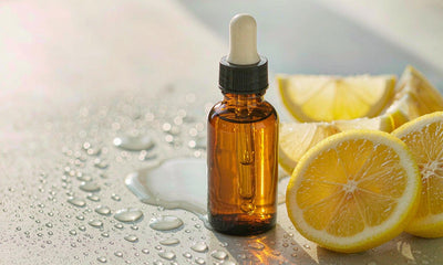 Plain unlabeled dropper bottle beside fresh lemon slices and water droplets on a light surface.