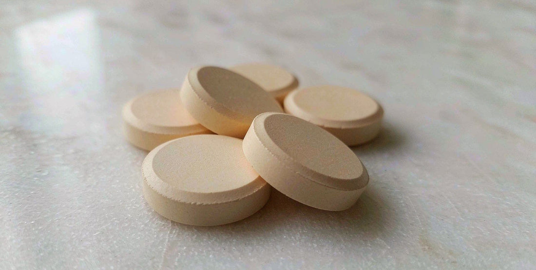 Macro view of smooth plain supplement tablets arranged on a bright white marble surface in natural light