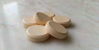Macro view of smooth plain supplement tablets arranged on a bright white marble surface in natural light