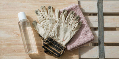 Flat lay of work gloves, a plain water bottle and a towel on a light wooden bench after physical work
