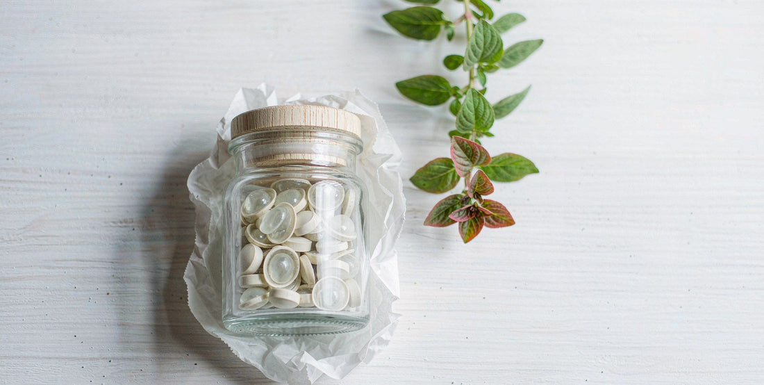 Flat lay of an unlabeled organ supplement jar with fresh herbs on a bright white wood surface