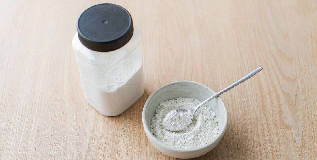 Plain unlabeled supplement bottle and a small bowl on a bright airy wooden table in daylight