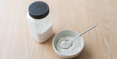 Plain unlabeled supplement bottle and a small bowl on a bright airy wooden table in daylight