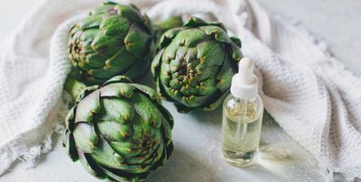 Fresh whole artichokes and a plain unlabeled dropper bottle on light linen, bright airy flat-lay