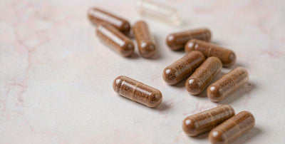 Macro view of plain beef liver supplement capsules on pale marble, soft focus
