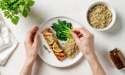 Hands plating a home-cooked salmon dinner with greens and grains in a bright kitchen