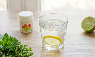 A glass of water with lemon beside a supplement jar