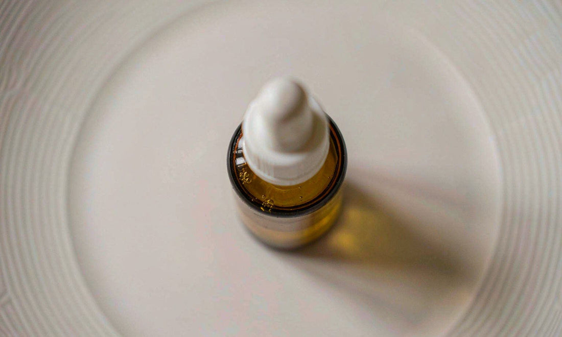 Plain unlabeled amber dropper bottle on a bright surface with a soft shadow