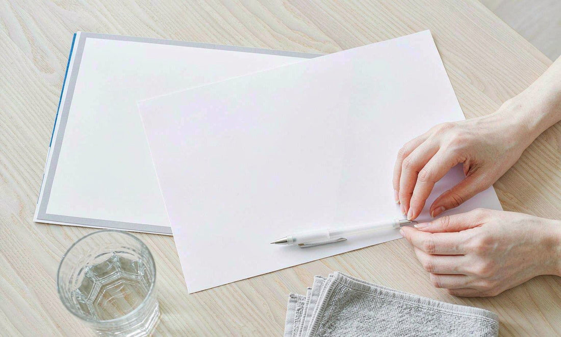 A lab paperwork flat lay with pen and water glass, sheet face down, hands entering from the side.