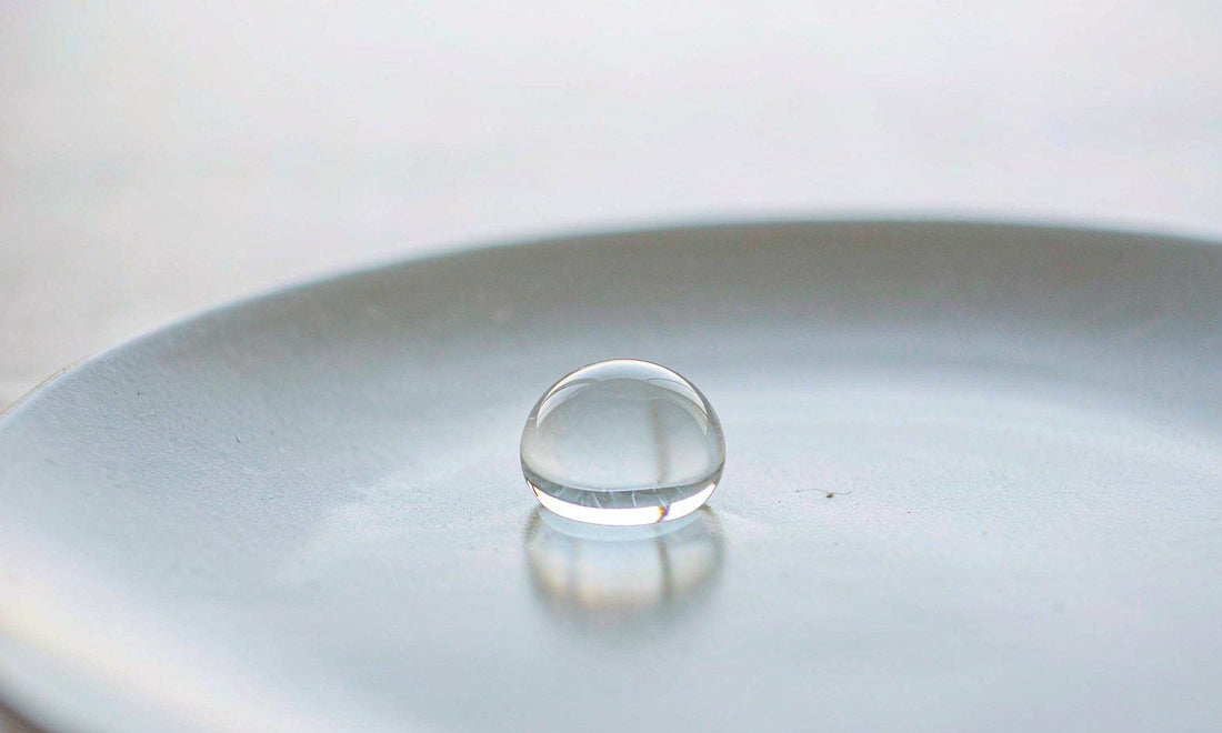Macro study of a single water droplet on a pale ceramic plate in soft cool morning light