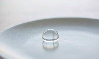 Macro study of a single water droplet on a pale ceramic plate in soft cool morning light