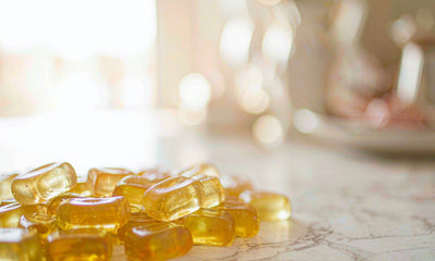 Extreme close-up of plain amber gummies on white marble in soft window light, everyday liver support