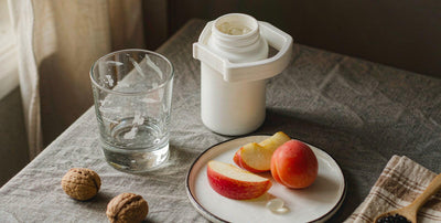 Flat lay breakfast with water and a plain supplement capsule in soft window light